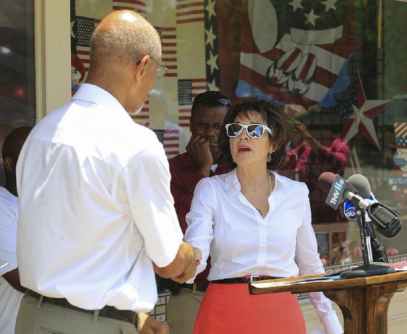 Dale Charles, president of the Arkansas NAACP, shakes hands Friday afternoon with Arkansas Flag and Banner owner Kerry McCoy after calling for her to quit selling Confederate flags at her Little Rock business.