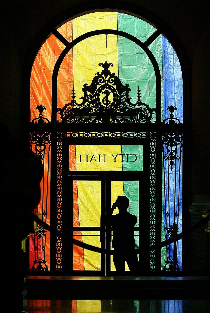 A large rainbow flag hanging in San Francisco’s City Hall draws a photographer’s interest Friday after the U.S. Supreme Court ruling giving same-sex couples the right to marry nationwide.