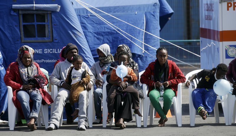 Migrants wait near a red cross tent after disembarking from the Belgian Navy Vessel Godetia at the Trapani harbor, Sicily, Italy, Wednesday, June 24, 2015. Hundreds of migrants were rescued Tuesday by the Godetia Belgian Navy Vessel, part of a EU Navy Vessels fleet taking part in the Triton migrants rescue operations.