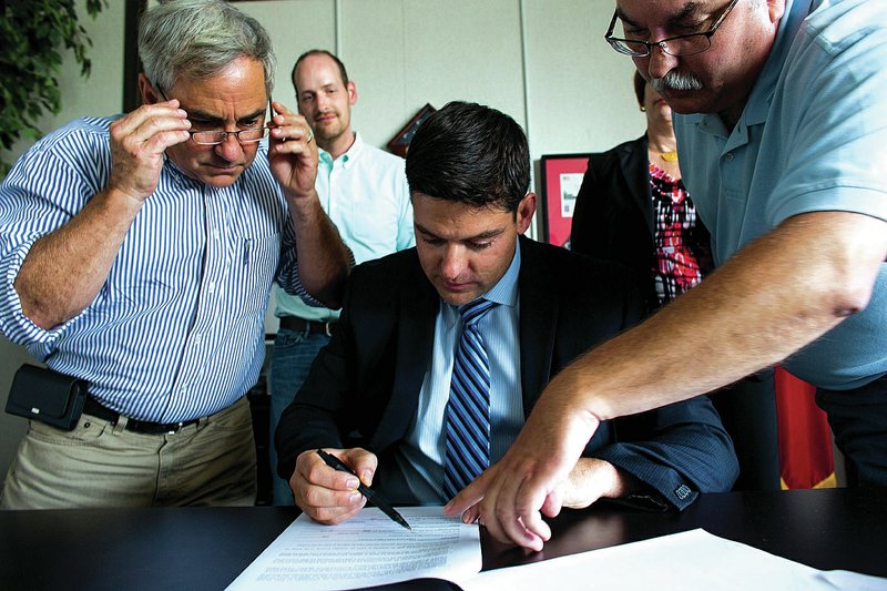 Arkansas Department of Veterans Affairs Director Matt Snead signs a contract with Steve Craig (left) of Craig Custom Construction to build a veterans home in North Little Rock. With them is Jim Thacker (right) with architecture firm Polk Stanley Wilcox.