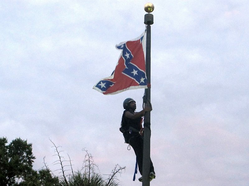 Bree Newsome of Charlotte, N.C., climbs a flagpole to remove the Confederate battle flag at a Confederate monument in front of the Statehouse in Columbia, S.C., on Saturday, June, 27, 2015. She was taken into custody when she came down. The flag was raised again by capitol workers about 45 minutes later. 
