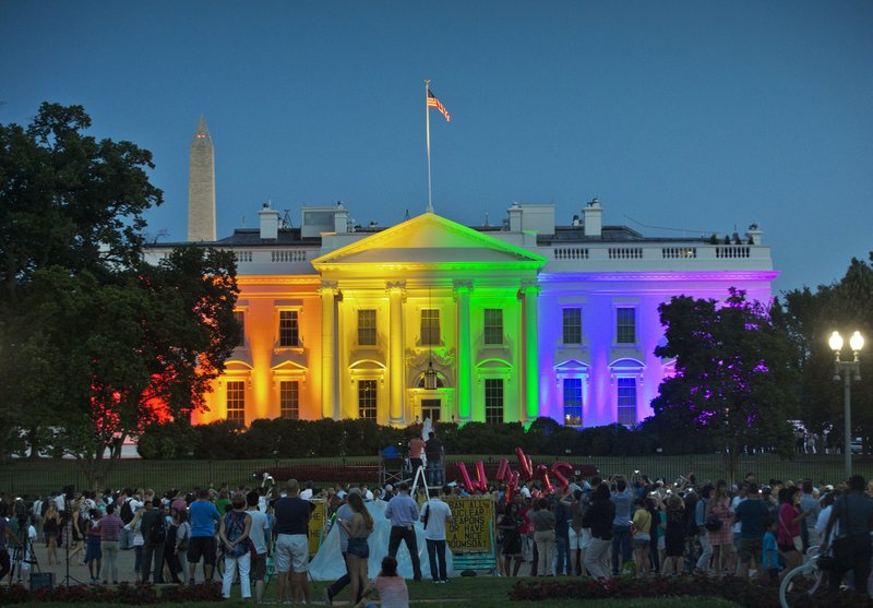 People gather in Lafayette Park to witness the White House being lit up in rainbow colors in commemoration of the Supreme Court's ruling to legalize same-sex marriage Friday, June 26, 2015, in Washington. Gay and lesbian couples in Washington and across the nation are celebrating Friday's ruling, which will put an end to same-sex marriage bans in the 14 states that still maintain them. 