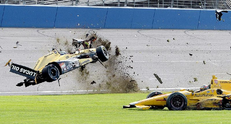 Ryan Briscoe flips through the infield grass on the final lap of Saturday’s IndyCar race at Auto Club Speedway in Fontana, Calif. He was not injured, but many drivers complained the aero kit mandated for the event made the racing dangerous.