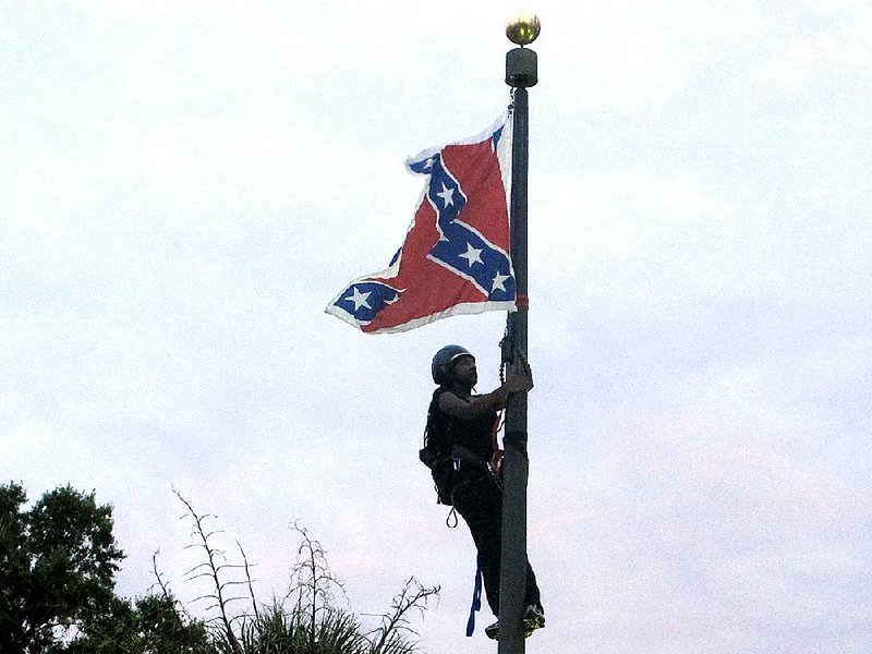 Bree Newsome of Charlotte, N.C., climbs a flagpole Saturday on the grounds of the South Carolina Statehouse to remove the Confederate flag. She and a man were taken into custody, and the flag was raised again by Capitol workers. 