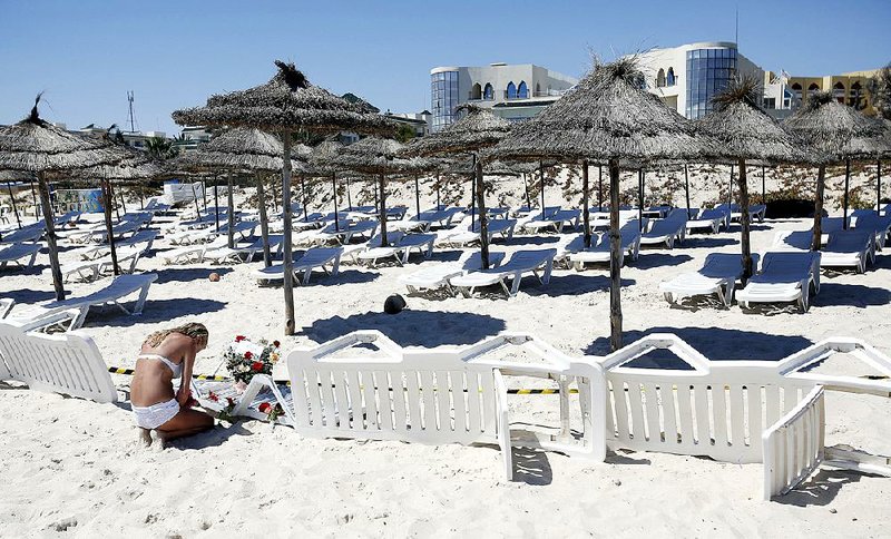 A woman lays flowers Saturday at the scene of Friday’s shooting at a beach resort in Sousse, Tunisia. 