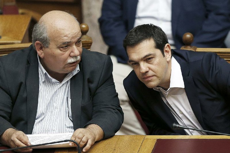 Greek Prime Minister Alexis Tsipras (right) chats Saturday with Greek Minister of Interior and Administrative Reconstruction Nikos Voutsis during an emergency Parliament session in Athens to discuss the government’s request for a referendum on economic measures sought by Greece’s creditors. 