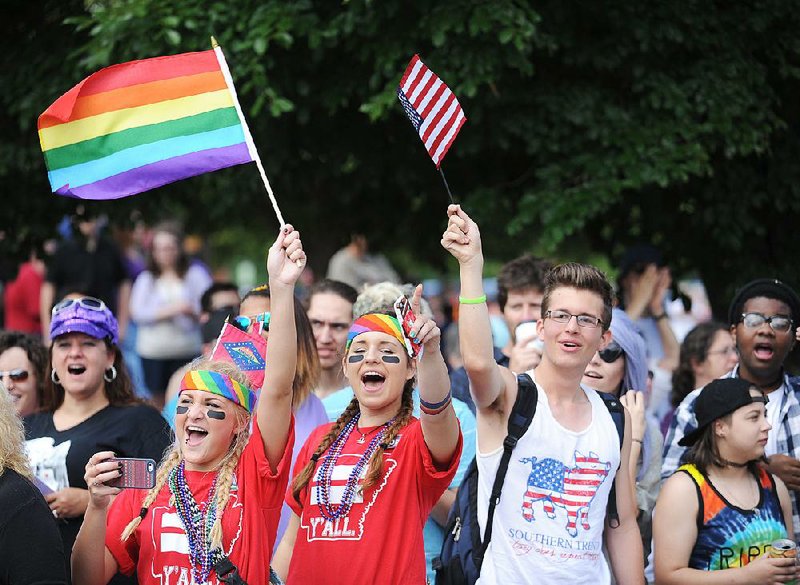 Cammi Tull (left), 16, and Madi Rotert, 16, both of Springdale, and Charles Hartman of Fayetteville celebrate Saturday during the Northwest Arkansas Pride Parade on Dickson Street in Fayetteville. The event drew a larger-than-normal crowd, organizers said. 