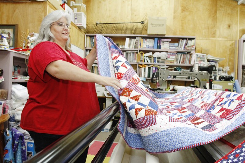 Nannette Moss of Freedom of Quilters at MNM Creations and Quilt Shop, works on a Quilt of Valor on a longarm machine, Wednesday. 