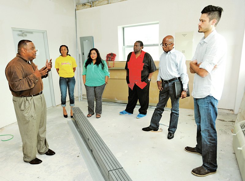 The Rev. Marcus Carruthers (from left) speaks Friday with volunteers and community leaders Stacy Harper, Maribel Tapia, Willie Johnson, Darryl Willis and Jacob Paul inside a building where officials plan to establish 1NWA, a nonprofit group to help at-risk youth and combat gang membership near the Springdale Municipal Airport on South Powell Street. For more photos, go to www.nwadg.com/photos.