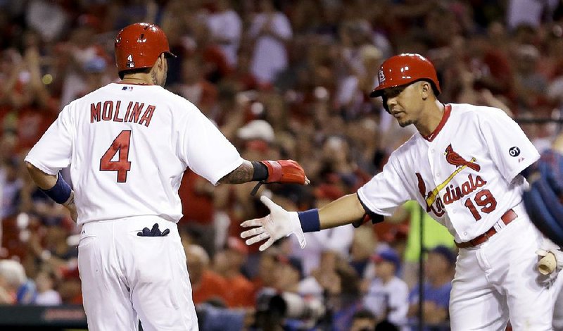 St. Louis catcher Yadier Molina (4) is greeted by Jon Jay after scoring during the second inning Sunday night against Chicago at Busch Stadium in St. Louis. The Cardinals beat the Cubs 4-1 in a game delayed by weather to move to a league-best 51-24. St. Louis is also 29-7 at home and has 22 come-from-behind victories this season, both of which are tops in the majors.