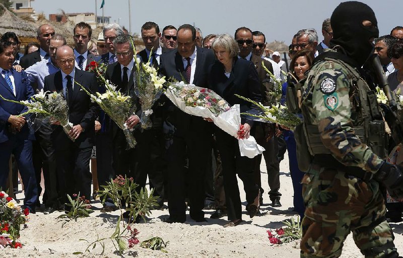 French Interior Minister Bernard Cazeneuve (second from left), German Interior Minister Thomas de Maiziere, Tunisian Interior Minister Mohamed Najem Gharsalli and British Home Secretary Theresa May stand Monday on a beach in Sousse, Tunisia, during a tribute to the 38 people killed in an attack last week.