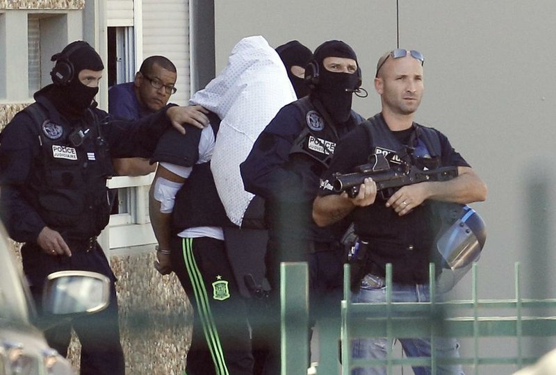 Yassine Salhi, the suspect in the beheading of a businessman, wears a towel over his head as he is escorted by police officers after they searched his home Sunday in Saint-Priest, outside Lyon, France.