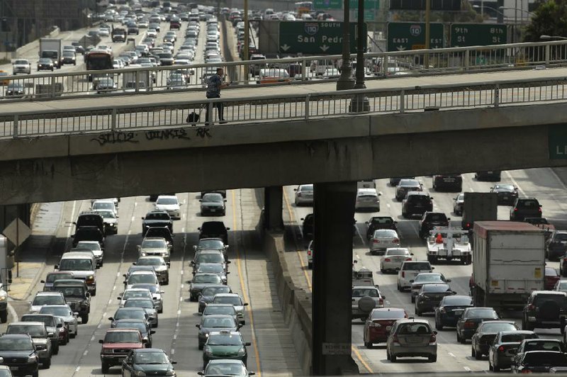 A man walks on the Wilshire Boulevard overpass as traffic slowly moves along the 110 Freeway in downtown Los Angeles in May.