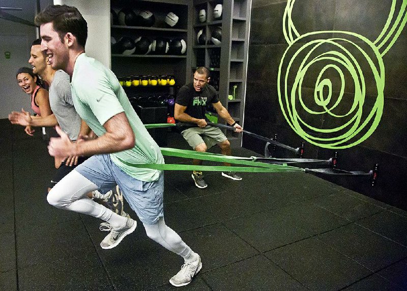 Gym instructor Javier Martinez (far right) trains clients how to run using resistance bands at the Fhitting Room boutique fitness studio in New York.
