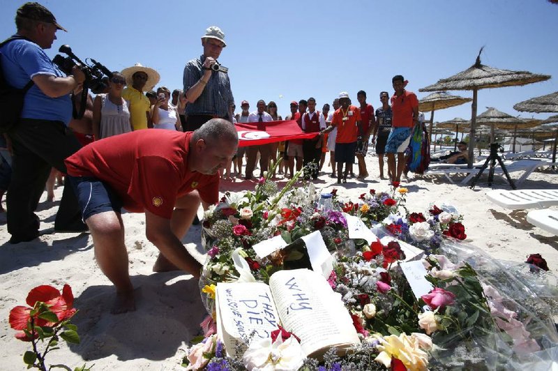 A man places flowers Sunday during a gathering at the scene of Friday’s deadly attack at a beach resort in Sousse, Tunisia.