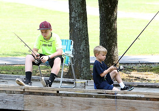 The Sentinel-Record/Richard Rasmussen Easton Bounds, 13, of Fayetteville, left, and Nicholas Reynolds, 6, of Hot Springs, fish off a dock Monday at Family Park. The boys were at the park with their grandmothers fishing for catfish under sunny skies using crickets and hot dogs for bait.