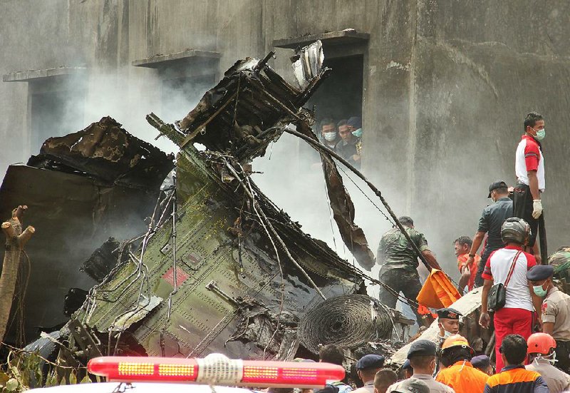 Military personnel on Tuesday search for victims around the wreckage of an air force transport plane that crashed into a residential neighborhood in Medan, North Sumatra, Indonesia.