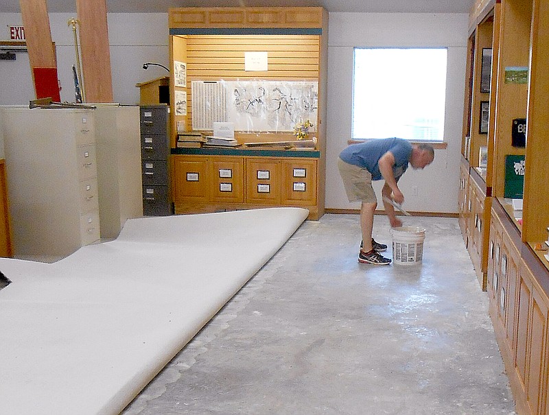 Submitted Dan Taylor puts glue down prior to the laying of new carpet in the back exhibit room.