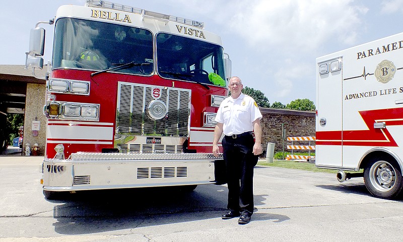 Brandon Howard/The Weekly Vista Bella Vista&#8217;s fire chief for eight years, Steve Sims stands in front of a fire truck July 23 at Fire Station No. 1, 103 Town Center West. Sims celebrated his 20th anniversary with the Bella Vista Fire Department on June 2.