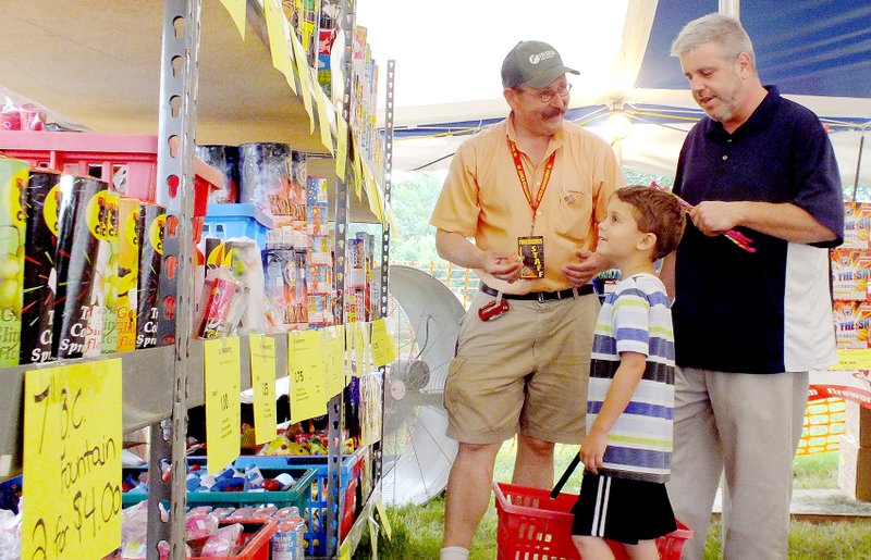 Brandon Howard/The Weekly Vista Darrin Horton, 7, and Kevin Corey, right, of Bella Vista shop for fireworks Friday, June 26, at Fireworks City while manager Doug Escue looks on. The tent is located at the parking lot of Wishing Spring Gallery, 8862 McNelly Road. Fireworks will be sold through July 5. The tent is open from 8 a.m. to 10 p.m. except on July 2-4, when it will be open from 7 a.m. to midnight.
