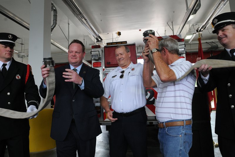 NWA Democrat-Gazette/FLIP PUTTHOFF Mayor Greg Hines (second from left), retiring Capt. Terry Douglas (center) and former captain Darrell Thomas uncouple a hose instead of cutting a ribbon Tuesday to dedicate Rogers&#8217; Fire Station No. 2. Thomas was on the Rogers Fire Department for 37 years.