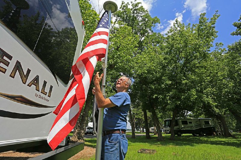 Bruce Theroux of Bradenton, Fla., puts up a flagpole with the American and the Army flags attached Wednesday after he and his wife, Sharon, arrived at the Maumelle Park campground and RV park in western Pulaski County.