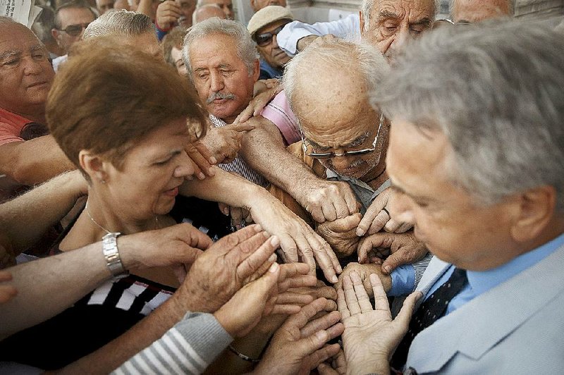 Greek pensioners grapple for a number to enter a bank in Athens on Wednesday so they can get some cash from their retirement checks. European creditors have been demanding changes in Greece’s pension system.