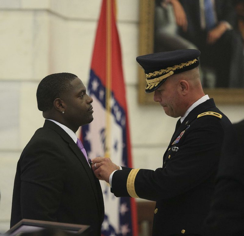 Maj. Gen. Jeffrey Snow pins a Purple Heart medal on former Army Pvt. Quinton Ezeagwula at a ceremony Wednesday at the state Capitol. “I was about to cry,” Ezeagwula said afterward.