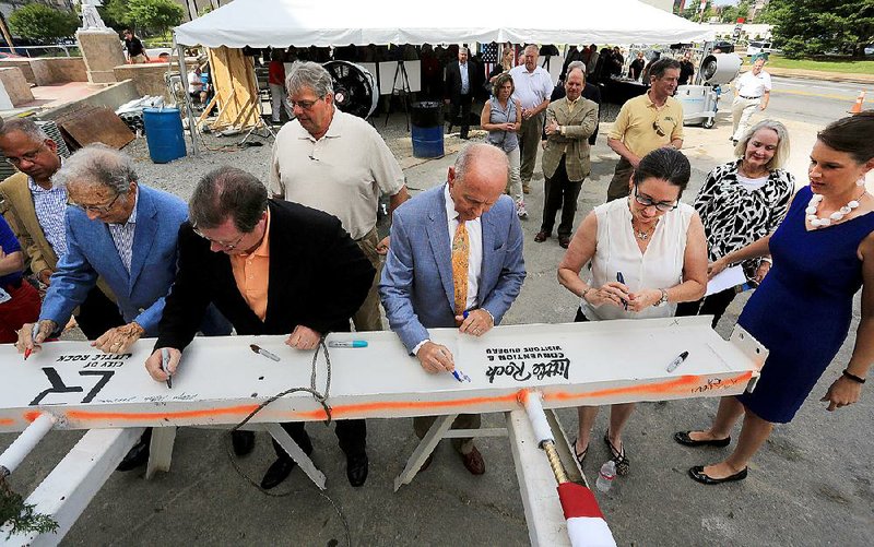 Little Rock City Manager Bruce Moore (from left), City Director at large Gene Fortson, Mayor Mark Stodola, former Mayor Jim Dailey and Capi Peck of the Little Rock Advertising and Promotion Commission sign a steel I-beam during a topping out ceremony for the Robinson Center’s new conference facility in Little Rock on Wednesday. Also shown are Ward 4 City Director Brad Cazort (behind Stodola) and Barbara Graves (far right), a former city director.