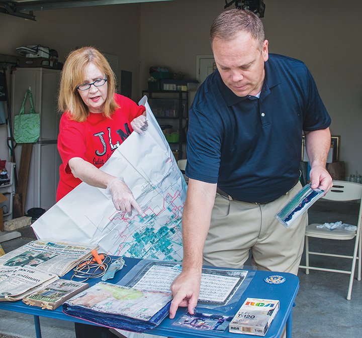 Cathy Dunn, former Julia Lee Moore Elementary School principal, and Kenny Clark, current principal, stand in the driveway of her home in Conway and look at items salvaged from a time capsule buried in September 1998 at the school on Country Club Lane. Dunn was the principal then, and she retrieved the time capsule after it was unearthed because of construction at the school. The original plan was to open the time capsule in 2025.