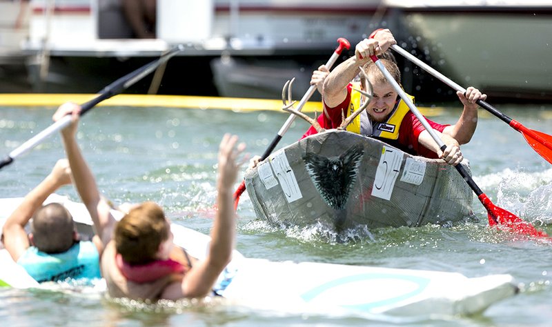 Justin Kish paddles while gaining on the competition’s boat, manned by Stephen, left, and Lukas Pate, which is falling apart feet from the finish line at Sandy Beach in Heber Springs during last year’s World Championship Cardboard Boat Races. Battling for the lead along with Kish are his boat mates Shawn Rhoades and Aaron Dorton.
