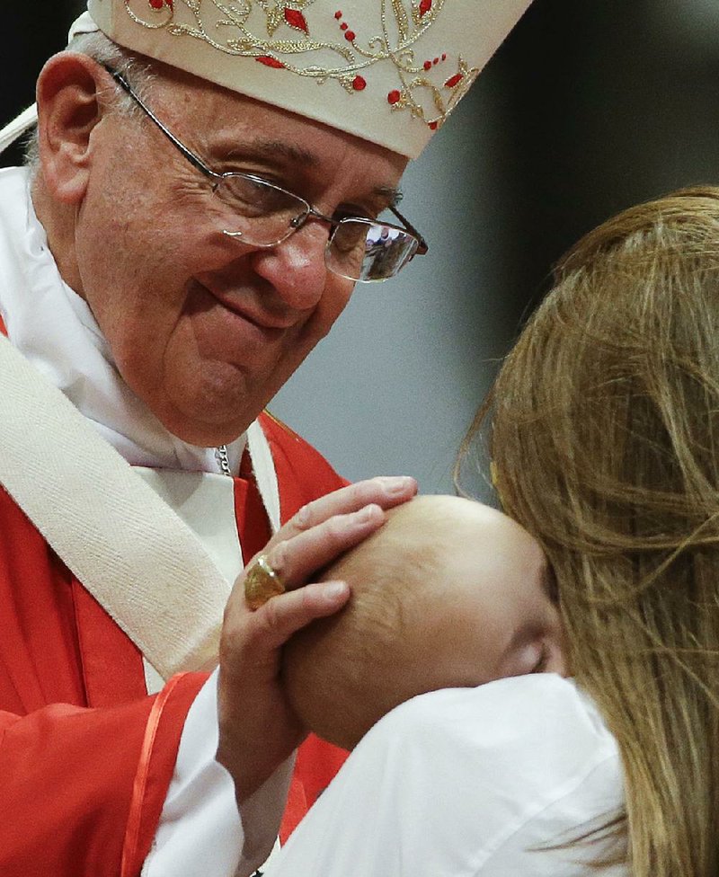 Pope Francis caresses a baby at St. Peter’s Basilica at the Vatican. The pope will visit the powerful and the poor during his trip to the United States in September.