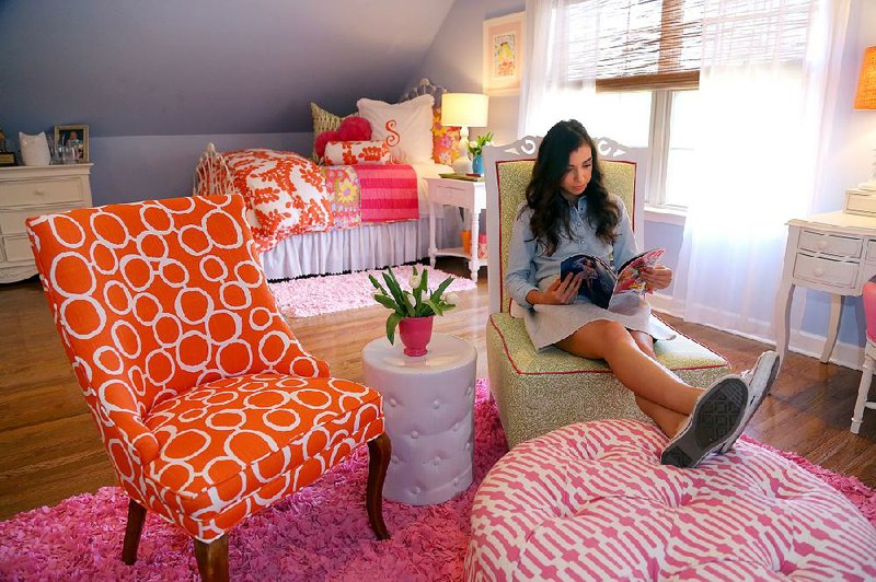 Stephanie Leake, 17, of Little Rock, reads a magazine in the sitting area of her bedroom. The spacious, gabled area features orange played against pink, with touches of green, interpreted in solids and patterns amid white furniture. Pine Cone Hill bedding set the color palette for the room. “Even if my style matures, I can tone down some of the brightness and have pops of it,” Leake says.