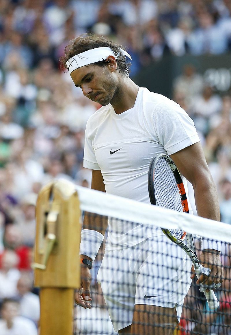 A dejected Rafael Nadal walks off the court Thursday at the All England Club after a four-set loss to qualifier Dustin Brown, Nadal’s fourth consecutive early exit from Wimbledon. 