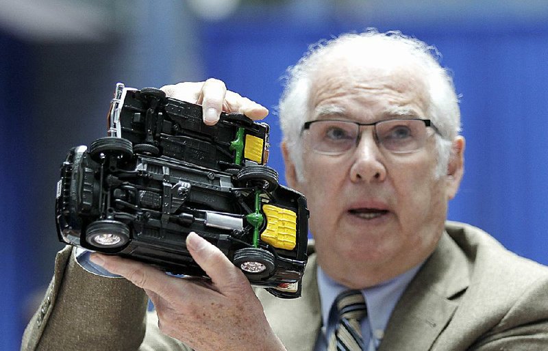 Automotive consultant Byron Bloch holds up Ford Pinto and Jeep Grand Cherokee SUV models during a hearing Thursday at the Transportation Department in Washington, D.C.