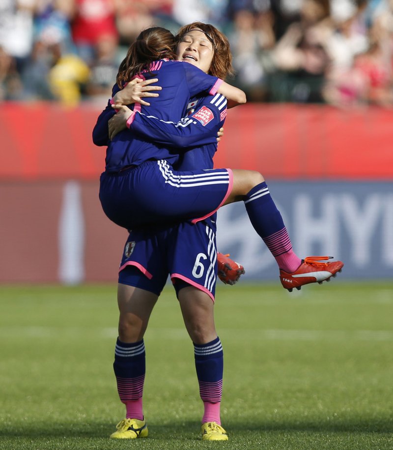 Japan's Nahomi Kawasumi jumps into the arms of Mizuho Sakaguchi (6) after the team's 2-1 win over England in a semifinal in the FIFA Women's World Cup soccer tournament, Wednesday, July 1, 2015, in Edmonton, Alberta, Canada.