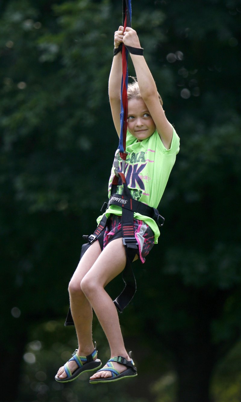 Lillee Lyons, 7, rides a zip line Tuesday as she participates in KampOut! presented by Kanakuk Kamps at Mount Sequoyah Retreat and Conference Center in Fayetteville. The week-long, high-energy camp — with ministry partners Church at Arkansas and The Grove Church — offered exciting activities, Bible study, worship discussions of acceptance and love. Another session of the camp runs July 13-17, sponsored by Central United Methodist Church in Fayetteville. 