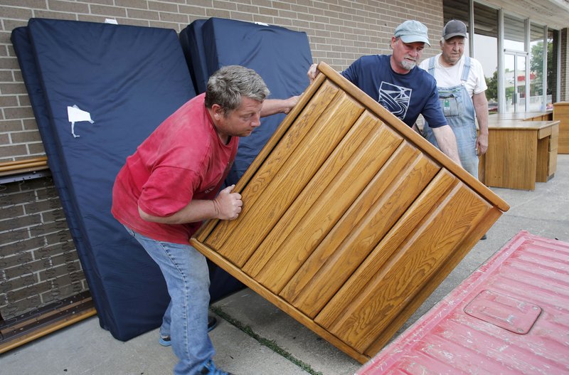 James Moreton (center), warehouse manager at LifeSource, helps David Shepherd (left) and Paul Shepherd load a dresser Tuesday onto a truck at LifeSource in Fayetteville. The University of Arkansas donated furniture from Gregson Hall to LifeSource for distribution to individuals and families.