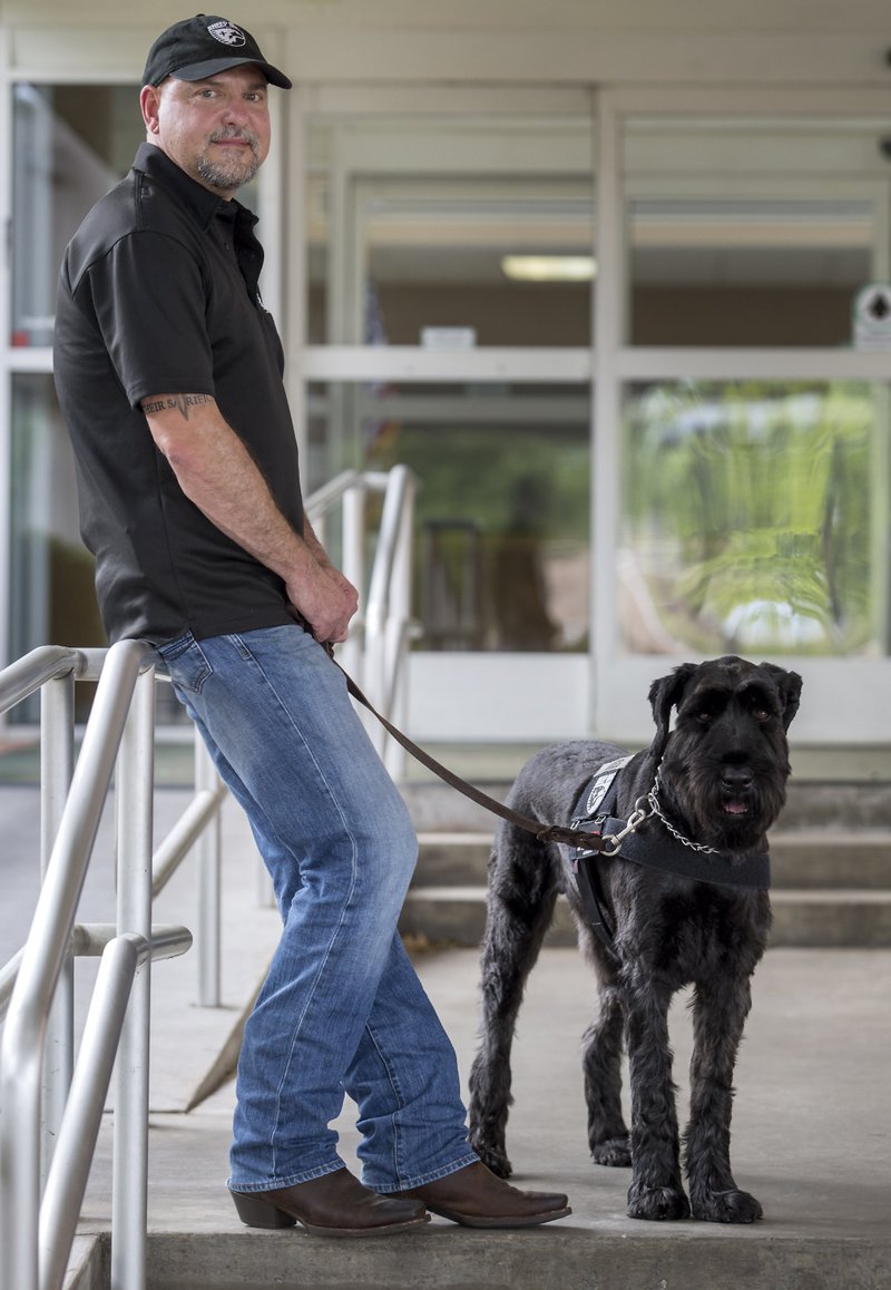 Dan Moss and Justice, a 3 1/2-year-old giant schnauzer, are seen June 22 outside the Center for Nonprofits in Rogers.