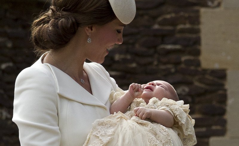 Britain's Kate the Duchess of Cambridge carries Princess Charlotte after taking her out of a pram as they arrive for Charlotte's Christening at St. Mary Magdalene Church in Sandringham, England, Sunday, July 5, 2015.