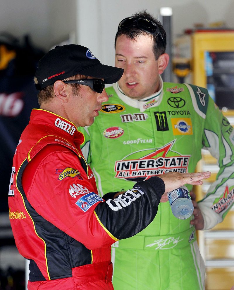 NASCAR drivers Kyle Busch (right) and Greg Biffle talk in the garage during a practice session Friday at Daytona International Speedway in Daytona Beach, Fla. Busch, who broke his right leg and left foot in a crash at Daytona in February, is calling for more tracks to remove grassy areas adjacent to racing surfaces.