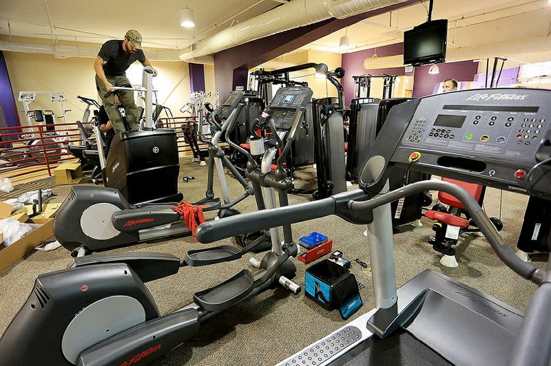 Eric Flint, with Alliance Transportation in Kansas City, Mo., works on exercise equipment being installed Thursday at the Bill Harmon Recreation Center in Sherwood.