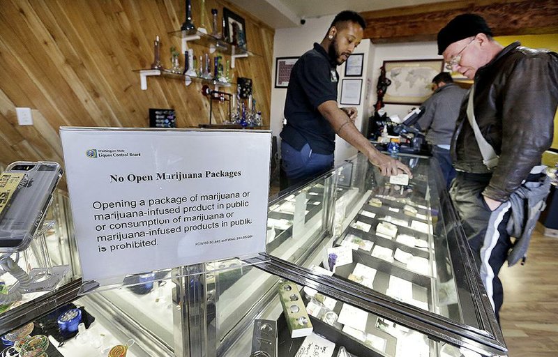 Cannabis City employee Will Bibbs (left) helps a customer looking over a display case of marijuana products at the Seattle shop in this file photo. 