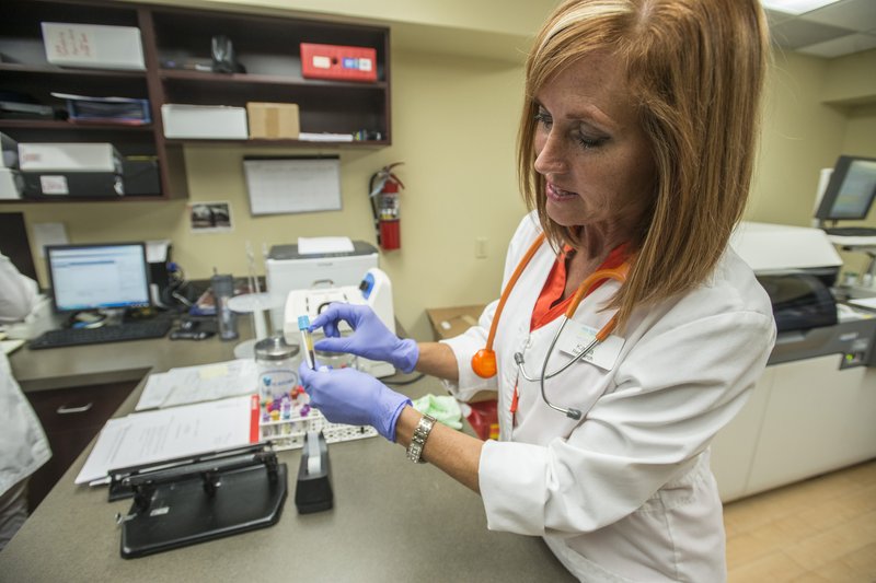 Kayla Kelly, medical assistant for research, demonstrates recently how she uses drawn blood to pull samples from to see how far along patients are in their treatments at Highlands Oncology Group in Fayetteville. The group is taking part in several research projects, including one that will track about 80 patients in 40 active clinic research projects testing new cancer drugs and treatments.