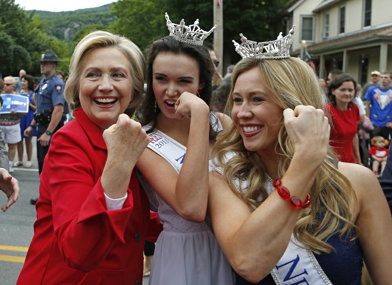 Democratic presidential candidate Hillary Rodham Clinton flexes her muscles with Miss Teen New Hampshire Allie Knault, center, and Miss New Hampshire Holly Blanchard, during a Fourth of July parade Saturday, July 4, 2015, in Gorham, N.H. 