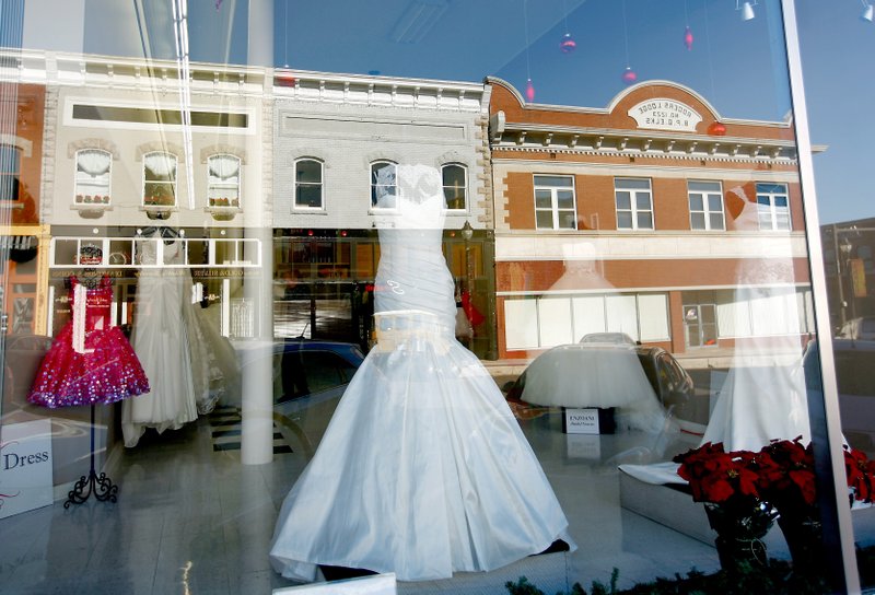 Downtown businesses are reflected in the storefront windows of White Dress Boutique in this January 2013 file photo. <br>
<strong><em>Correction:</strong></em> Owner Debbie Abbott, who bought the boutique in November 2013, moved the store to its current location at 116 W. Walnut St. A previous caption misidentified the owner.