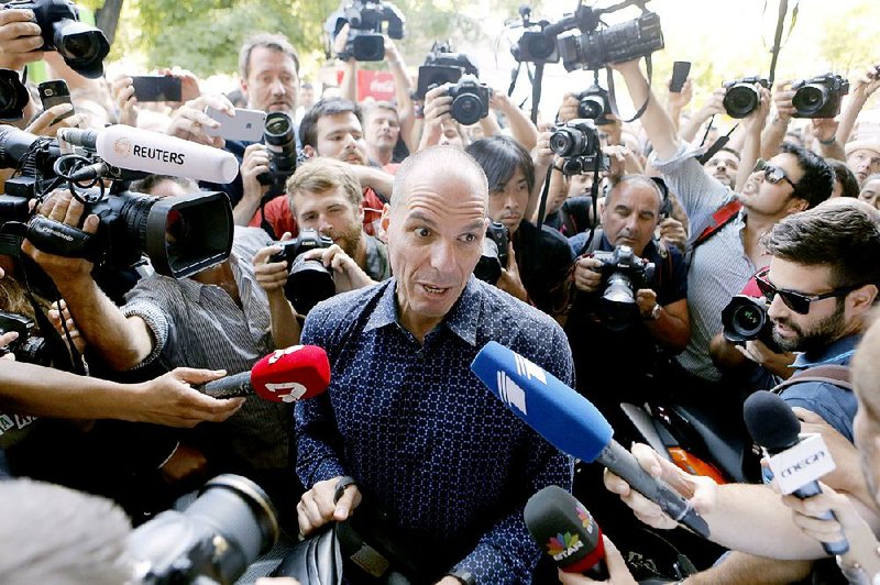 Outgoing Greek Finance Minister Yanis Varoufakis is surrounded by reporters as he tries to leave on his motorcycle Monday after resigning in Athens.