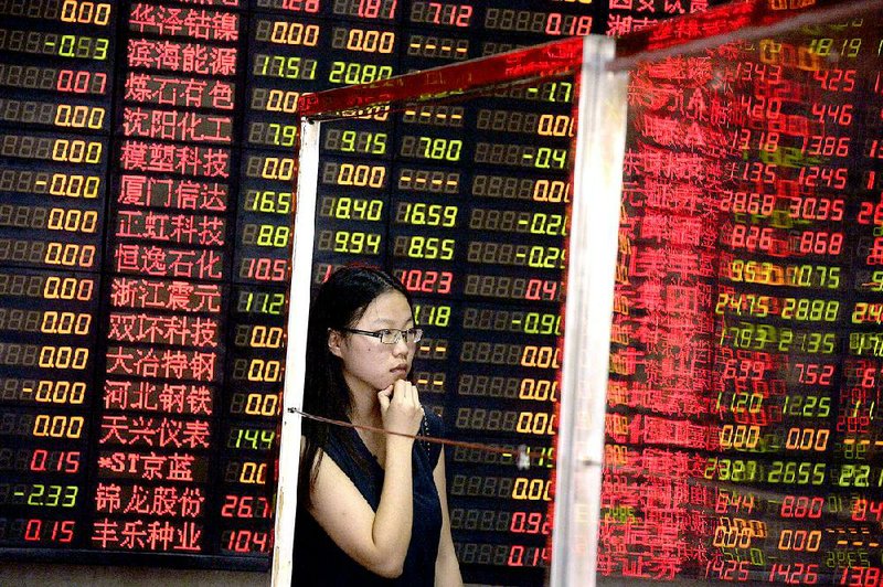 A Chinese woman stands behind a glass panel near stock prices displayed on a board at a brokerage house in Shanghai, China. Shares in state companies rose Monday after government promises of action to halt a slide in stock prices.