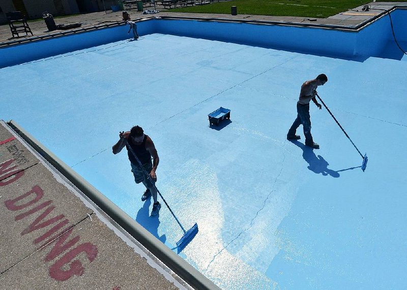 Employees of Advanced Concrete Floor Finishes of Findley Lake, N.Y., paint the floor of a swimming pool in Erie, Pa., in June.