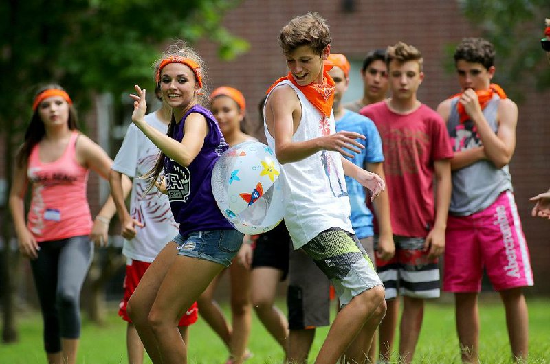 UCA Upward Bound Project student Emily White (left) and Argentine high school student Matias Moar crab-walk with a ball between them during a relay race on the University of Central Arkansas campus Wednesday in Conway.